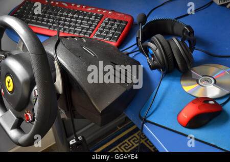 Plate-forme de jeu d'ordinateur - comprend le volant monté sur table top, claviers, casques, DVD, une souris à molette rouge et mat. Banque D'Images