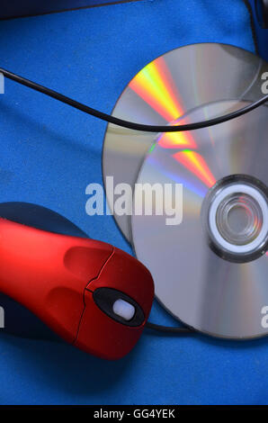 Un défilement de la souris PC rouge, 2 DVD de jeu reposent sur un tapis de souris. Banque D'Images