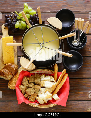 Set d'ustensiles traditionnels pour la fondue, avec du pain, du fromage et du raisin Banque D'Images