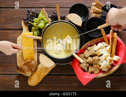 Set d'ustensiles traditionnels pour la fondue, avec du pain, du fromage et du raisin Banque D'Images