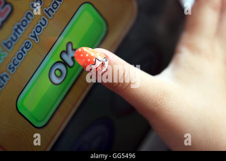 Sept ans filles doigt frappant OK sur une app Banque D'Images