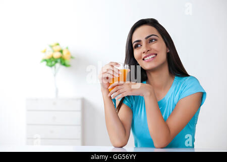 Young woman holding verre de jus d'orange à la maison Banque D'Images