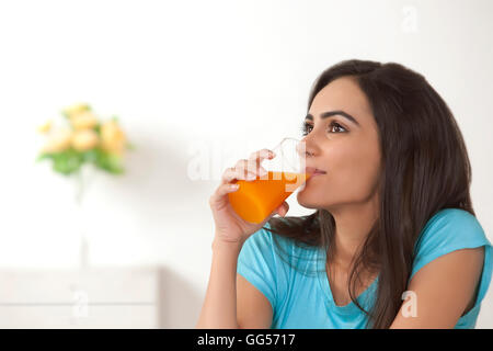 Young woman drinking orange juice à la maison Banque D'Images