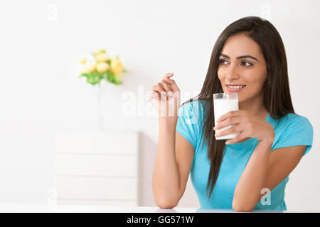 Belle jeune femme avec un verre de lait à la maison Banque D'Images