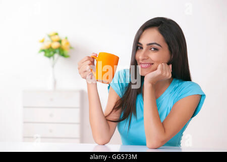 Portrait of happy young woman having coffee at home Banque D'Images