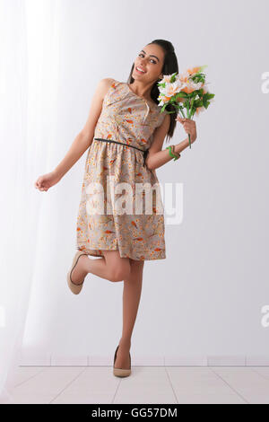 Portrait of happy young woman holding Flowers at home Banque D'Images