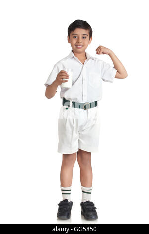 Portrait de jeune garçon en uniforme d'flexing muscles tout en maintenant le lait sur fond blanc Banque D'Images