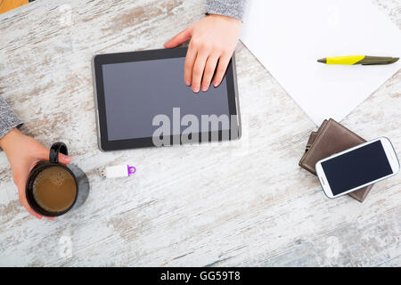La main d'une femme à une table useing une tablette. Banque D'Images