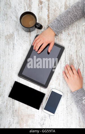 La main d'une femme à une table useing une tablette. Banque D'Images