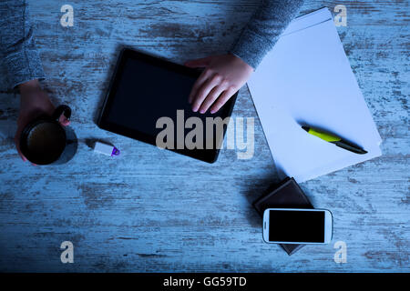 La main d'une femme à une table useing une tablette. Banque D'Images