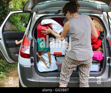 Jeune mère de charger les bagages dans le coffre de la voiture avant le départ Banque D'Images