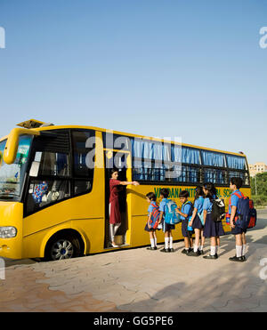 Les enfants de l'école montent sur un autobus scolaire Banque D'Images