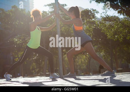 Les jeunes athlètes féminines faisant exercice s'étendant par pôle sur street Banque D'Images