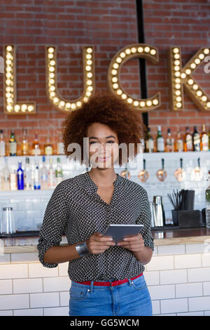 Portrait of happy young woman with a digital tablet at bar Banque D'Images
