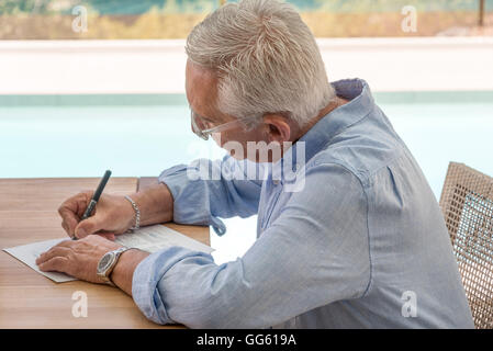 Man doing paperwork at poolside Banque D'Images