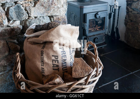 Sac de tourbe dans une maison à Outer Hebrides pour utilisation comme carburant dans poêle à bois Morsø en arrière-plan. Banque D'Images