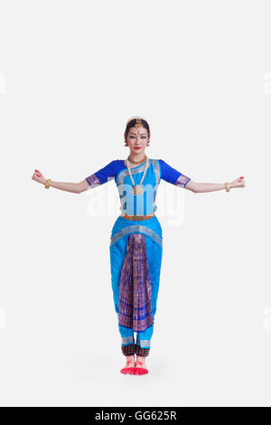 Portrait of young woman with arms outstretched performing Bharatanatyam against white background Banque D'Images