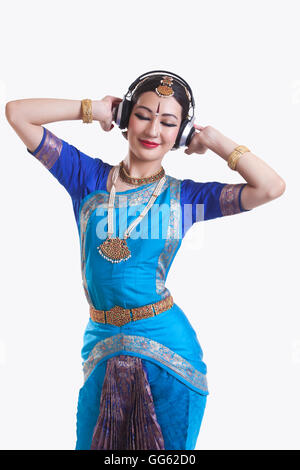 Danseuse de bharatanatyam listening music on headphones over white background Banque D'Images