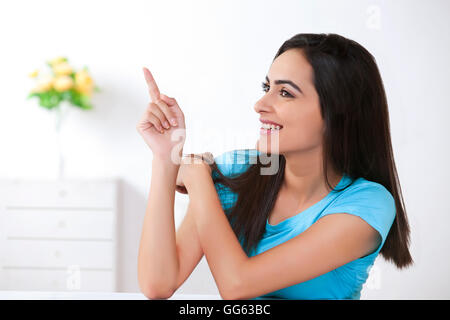 Happy young woman showing quelque chose à la maison Banque D'Images