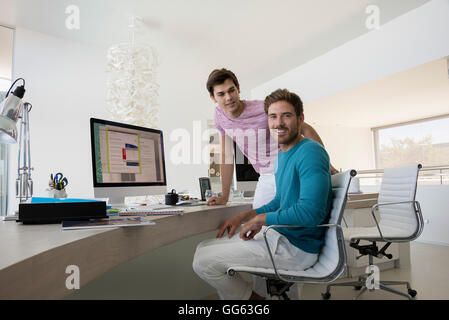 Heureux les jeunes hommes travaillent ensemble sur ordinateur dans un bureau Banque D'Images