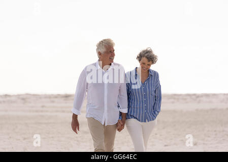 Happy senior couple walking on beach Banque D'Images