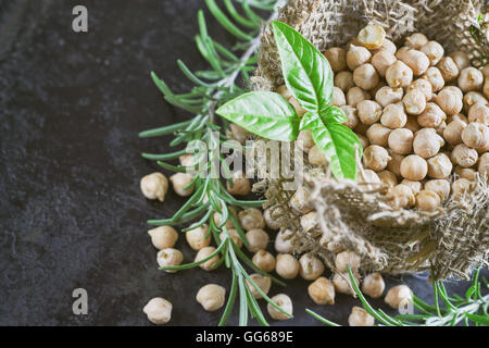 Pois chiches (garbanzo) avec le basilic dans de petits sac de toile noire sur fond rustique. Top View with copy space Banque D'Images