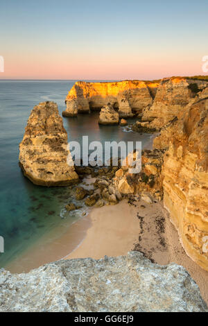 Lever du soleil sur les falaises et l'eau turquoise de l'océan, Praia da Marinha, Caramujeira, Municipalité de Lagoa, Algarve, Portugal Banque D'Images