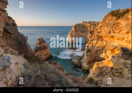 Lever du soleil sur les falaises et l'eau turquoise de l'océan, Praia da Marinha, Caramujeira, Municipalité de Lagoa, Algarve, Portugal Banque D'Images