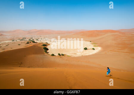 Une femme court en bas du sommet des dunes de sable de Sossusvlei, Namibie, Afrique Banque D'Images