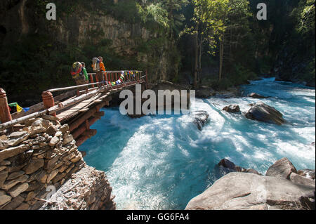 Les randonneurs traversant un pont de bois entre l'Chhepka et hôpital Amchi en Dolpa, une région reculée du Népal, Himalaya, Népal, Asie Banque D'Images