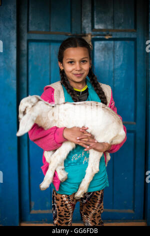 Une petite fille tenant une chèvre dans un petit village au Népal, Asie Banque D'Images