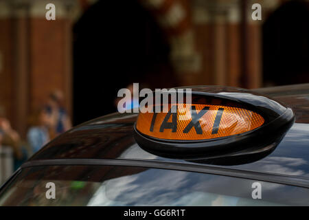 L'orange enseigne sur le toit d'un taxi noir de Londres avec les rues de la ville en arrière-plan. Banque D'Images