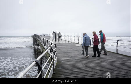 Les personnes âgées de marcher sur la jetée victorienne Saltburn lors d'une froide journée d'octobre, gris. Marseille par la mer, en Angleterre. UK Banque D'Images