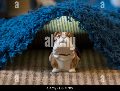 Un bouledogue tirelire se mettre à couvert sous un tapis à la maison Banque D'Images