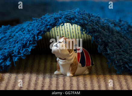 Un bouledogue tirelire se mettre à couvert sous un tapis à la maison Banque D'Images