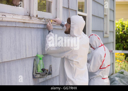 Deux peintres maison dans le hazmat convient à la dépose de la peinture au plomb à partir d'une vieille maison. Banque D'Images