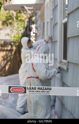 Deux peintres maison dans le hazmat convient à la dépose de la peinture au plomb à partir d'une vieille maison. Banque D'Images