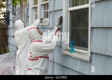 Deux peintres maison dans le hazmat convient à la dépose de la peinture au plomb à partir d'une vieille maison. Banque D'Images