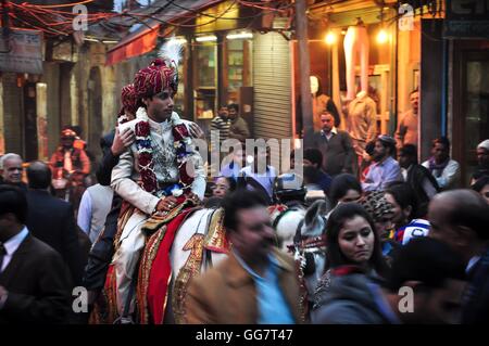Groom sur un cheval blanc dans le cadre d'une procession de mariage indien. Rues de Chandni Chowk, Old Delhi, Inde. Banque D'Images