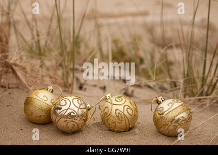 Boules de Noël décoratives disposées en sable avec du bois flotté sur une plage en Nouvelle-Zélande pour un Noël de l'hémisphère Sud d'été Banque D'Images