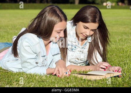 Belle jeune fille sur l'herbe et de la lecture, livre de l'été fond contre green park. Banque D'Images