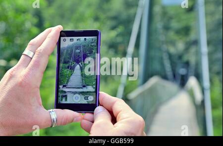 Vue sur l'écran du téléphone lors de la prise d'une photo de pont dans la nature. L'homme est maintenant le téléphone mobile en main et taki Banque D'Images