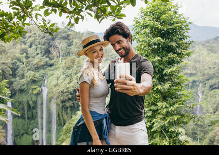 Couple de s'amuser ensemble en plein air sur leurs vacances. Taking self portrait with camera phone après une randonnée à belle waterfal Banque D'Images