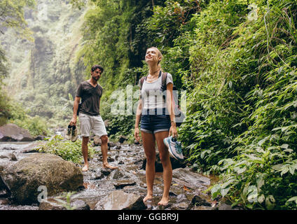Couple à travers le ruisseau. L'homme et la femme à la marche de la forêt près d'une crique. Tourisme nature randonnée pédestre. Banque D'Images