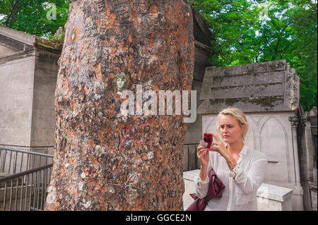 Un touriste photographie un arbre couvert de graffitis à côté de la tombe de Jim Morrison au cimetière du Père-Lachaise à Paris, France. Banque D'Images