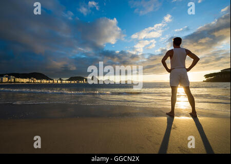 Silhouette d'un homme debout en face de golden sunrise beach sur la plage de Copacabana à Rio de Janeiro, Brésil Banque D'Images