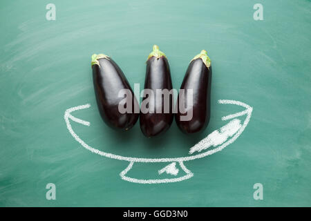 Aubergines fraîches savoureuses sur green chalkboard Banque D'Images