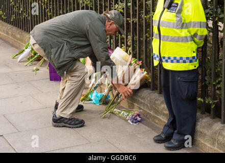 Un homme jette des fleurs près de la scène d'un coup de poignard fatal à Russell Square, Londres, après un homme de 19 ans a été arrêté, soupçonné de meurtre après qu'une femme a été tué et cinq personnes blessées dans un couteau rampage dans le centre de Londres. Banque D'Images