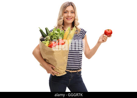 Blond woman holding une tomate dans une main et un sac de courses dans l'autre isolé sur fond blanc Banque D'Images