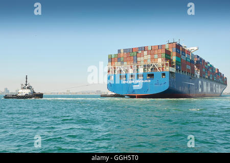 Le géant, CMA CGM Centaurus, porte-conteneurs est manoeuvré vers Pier J dans le terminal à conteneurs de Long Beach, Los Angeles, Californie, USA. Banque D'Images